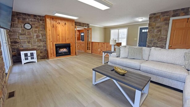 A living room with a stone wall, a fireplace, a sofa, and a coffee table.