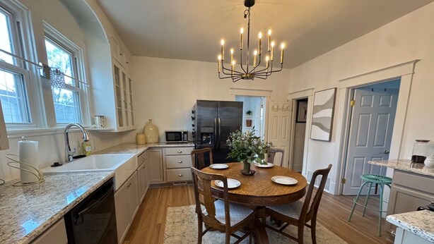A kitchen with a dining area, featuring a central island, wooden chairs, a chandelier, and a refrigerator.