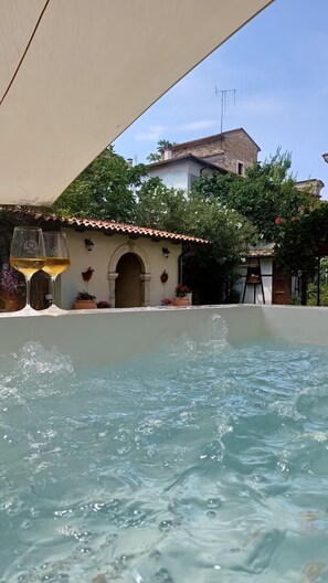 A hot tub with water splashing, a building with a tiled roof, and potted plants. - House in the historic center of Sulmona with a garden and a hot tub (Sulmona)