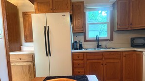 A kitchen with wooden cabinets, a white refrigerator, a sink, and a window.