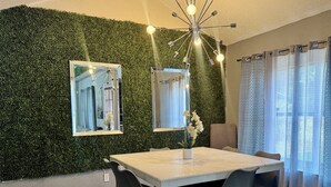 A dining area with a green wall, a chandelier, and a large mirror.