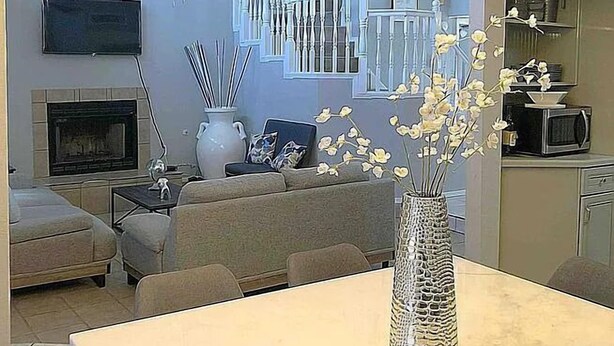 A modern living room with a dining table, a fireplace, and a kitchen area.