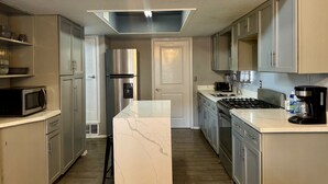 A modern kitchen with a central island, stainless steel appliances, and light-colored cabinetry.
