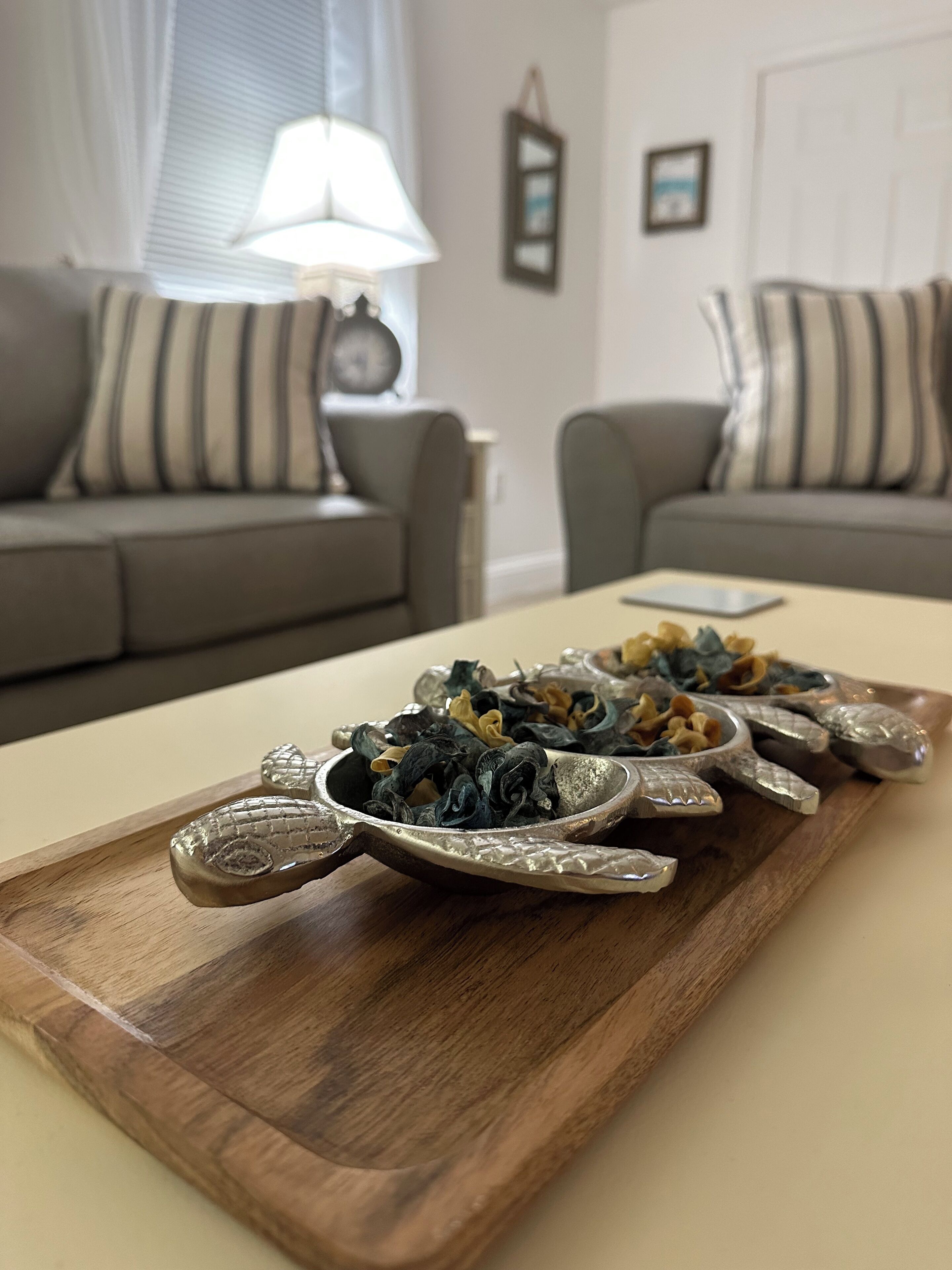 A wooden serving tray with food items on a table in a living room.