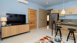 Une cuisine moderne avec des meubles en bois, un four encastré et un coin repas équipé de tabourets.