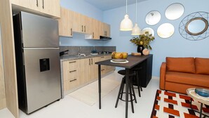 A modern kitchen with a stainless steel refrigerator, wooden cabinets, a central island with stools, and a blue wall with circular mirrors.