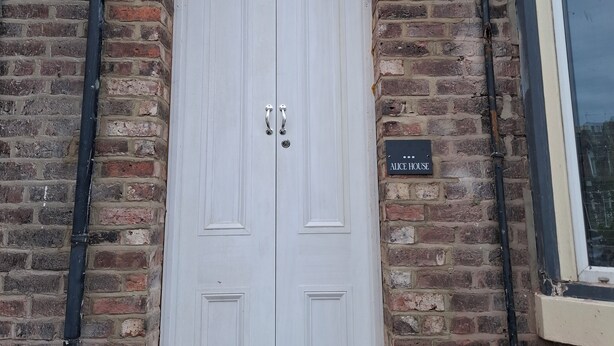 A white double door with a small arched window above it, set in a brick wall. A sign reading "Alice House" is visible to the right of the door. - Stylish 4-Bed  with Sauna /Jacuzzi City Centre Location near Stadium of Light (Sunderland)