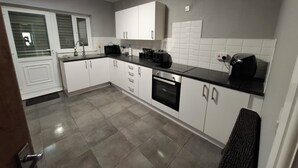 A modern kitchen with white cabinets, a black countertop, and a built-in oven. - Stylish 4-Bed  with Sauna /Jacuzzi City Centre Location near Stadium of Light (Sunderland)