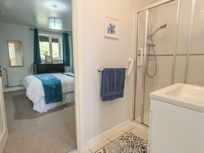 A bedroom with a bed, a bathroom with a shower, and a hallway. - June Cottage (Dorchester)