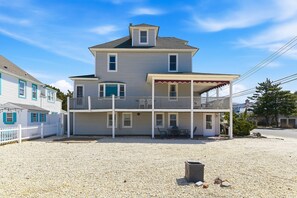 A two-story house with a balcony, a covered porch, and a gravel driveway. - Seaside Park 3BR Beach Retreat Ocean Block, Patio, Grill & Parking (Seaside Park)