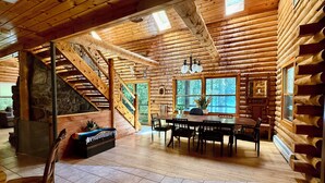 A log cabin interior with a dining area, a staircase, and large windows. - Welcoming 4-bedroom cabin in Chesterville (Chesterville)