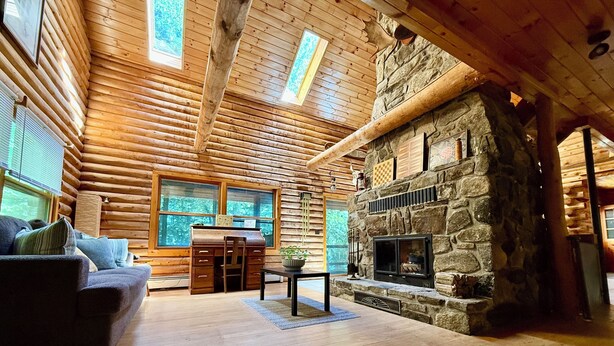 A log cabin interior with a stone fireplace, wooden walls, and a cozy seating area. - Welcoming 4-bedroom cabin in Chesterville (Chesterville)