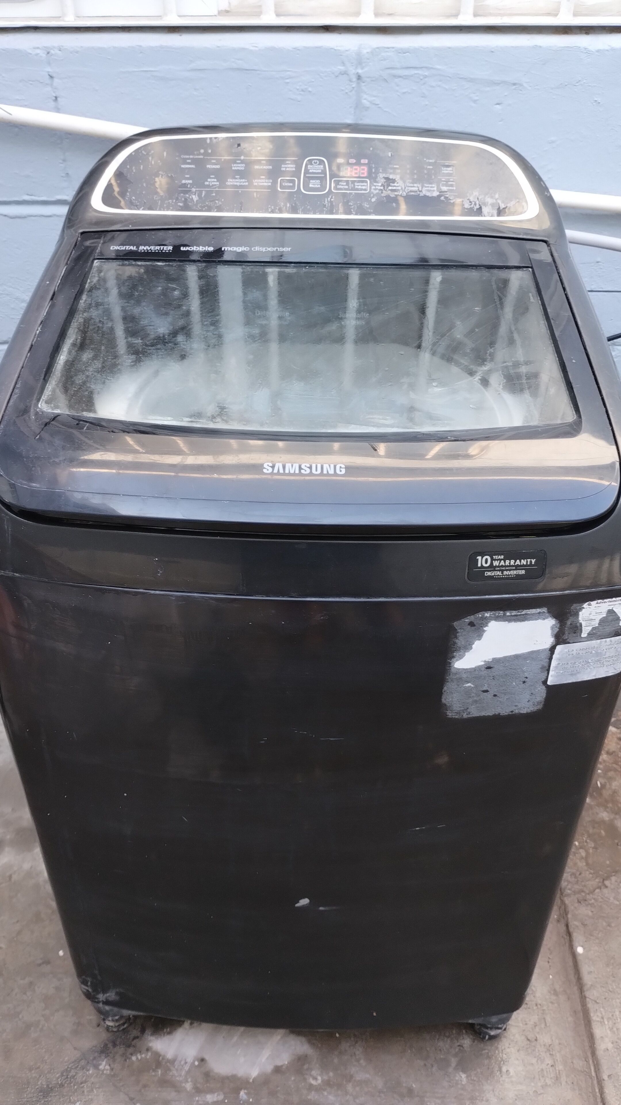A black Samsung refrigerator with a digital display, a 10-year warranty sticker, and a digital inverter label.