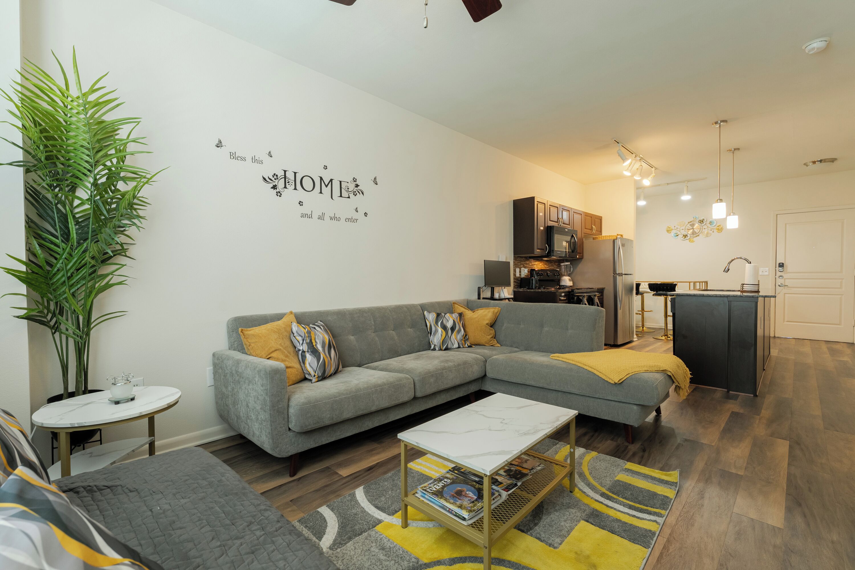 A modern living room with a grey sofa, a coffee table, and a large potted plant.