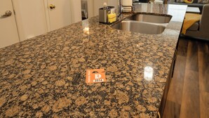 A kitchen with granite countertops, a stainless steel sink, and a parking permit holder. - 1-bedroom apartment in The Domain with infinity pool+fitness room+2025 smart TV (Leander)