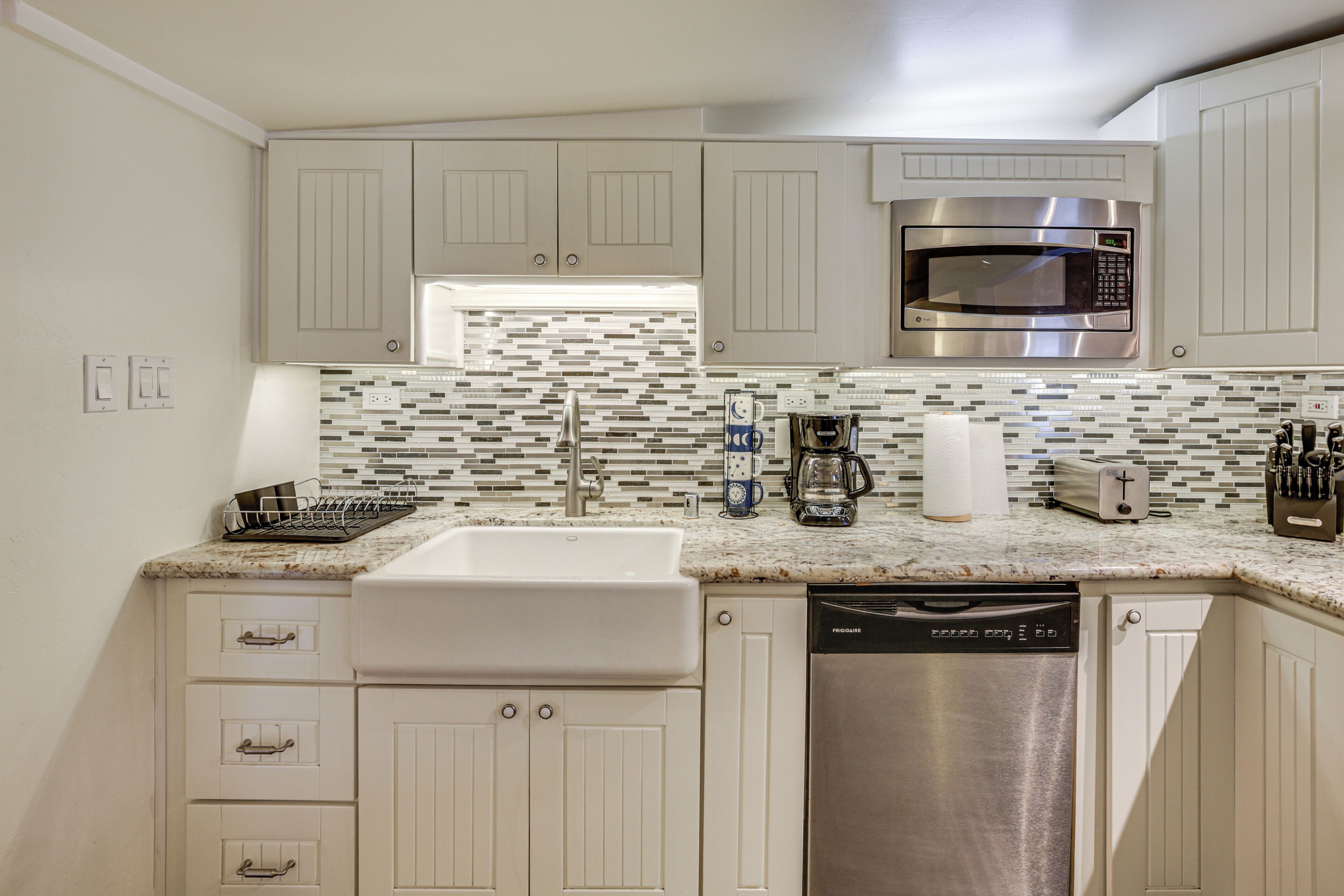 A kitchen with a stainless steel microwave, a coffee maker, and a dishwasher.