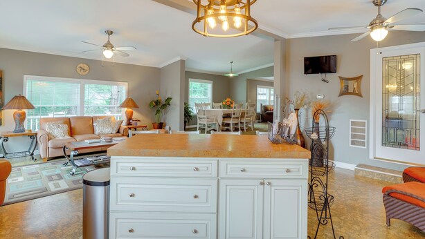 A spacious living room with a large island, ceiling fans, and a dining area in the background. - 1 Mi to Silver Lake Sand Dunes: Deck, Grill & Yard (Mears)