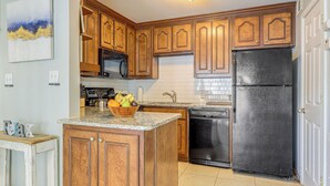 Una cocina con armarios de madera, un refrigerador negro, un microondas y un lavabo.