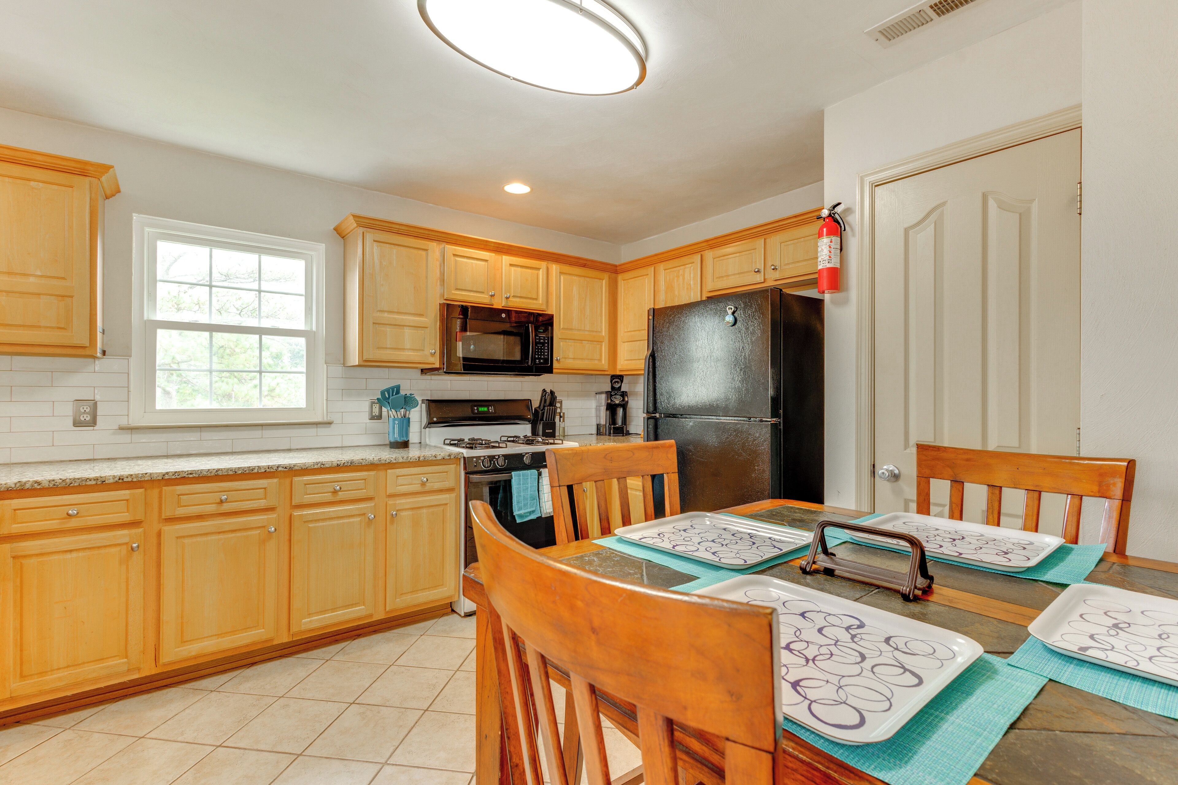 A kitchen with wooden cabinets, a microwave, stove, and a refrigerator.