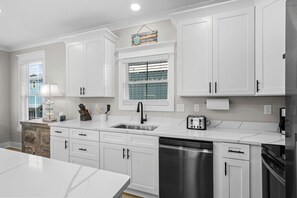 A modern kitchen with white cabinetry, a stainless steel dishwasher, and a toaster. - Luxury Beach House, Elevator, Golf Cart & Grill! (Myrtle Beach)