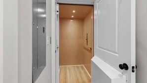A narrow hallway with a wooden door leading to a room with a wooden floor. - Luxury Beach House, Elevator, Golf Cart & Grill! (Myrtle Beach)