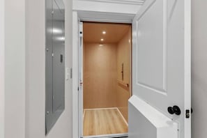 A narrow hallway with a wooden door leading to a room with a wooden floor. - Luxury Beach House, Elevator, Golf Cart & Grill! (Myrtle Beach)