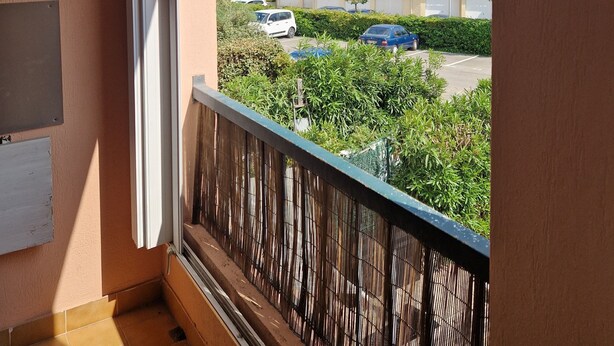 A balcony with a view of a parking area and buildings in the distance.