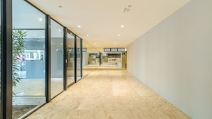 A modern hallway with glass doors, a tiled floor, and recessed lighting. - Apart w/ a Suite 290m From Vaca Brava Park Obd2108 (Goiânia)