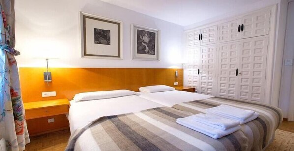 A hotel room with two beds, a wooden headboard, a wardrobe, and two framed pictures on the wall. - Hotel Rural Victoria by Bossh Hotels (JĂ¡baga)