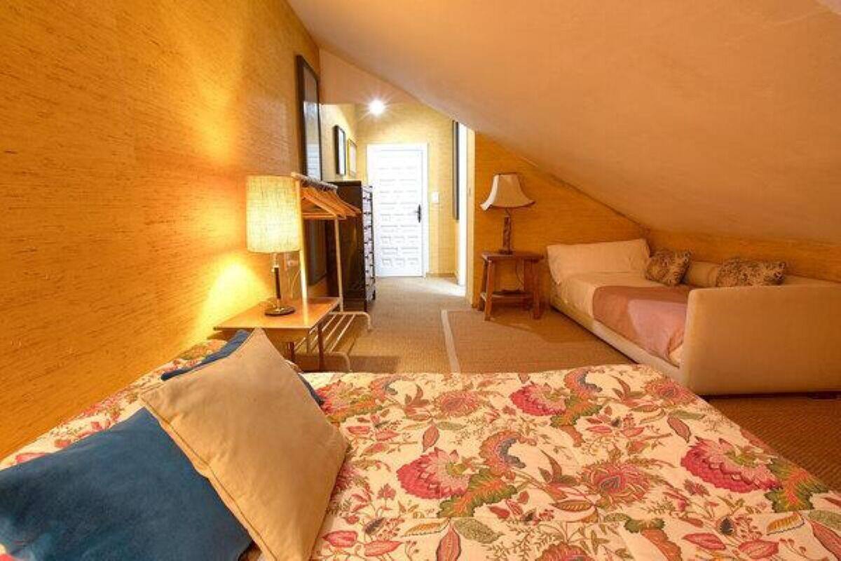 A cozy room with a bed, a small table, a lamp, and a sofa.