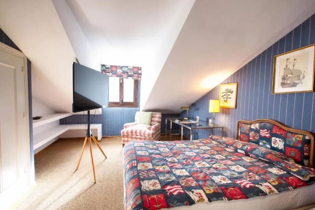 A bedroom with a bed, a desk, a chair, and a window.