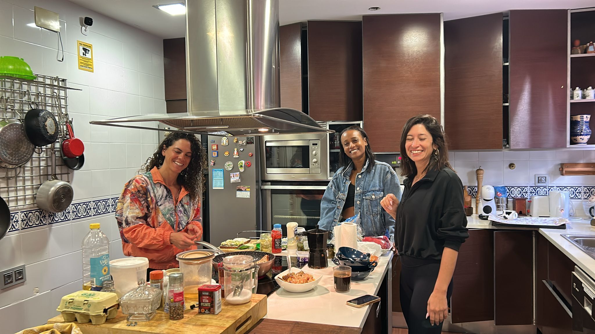 Una cocina moderna con electrodomésticos de acero inoxidable, un colgador para ollas y varios alimentos sobre la encimera.