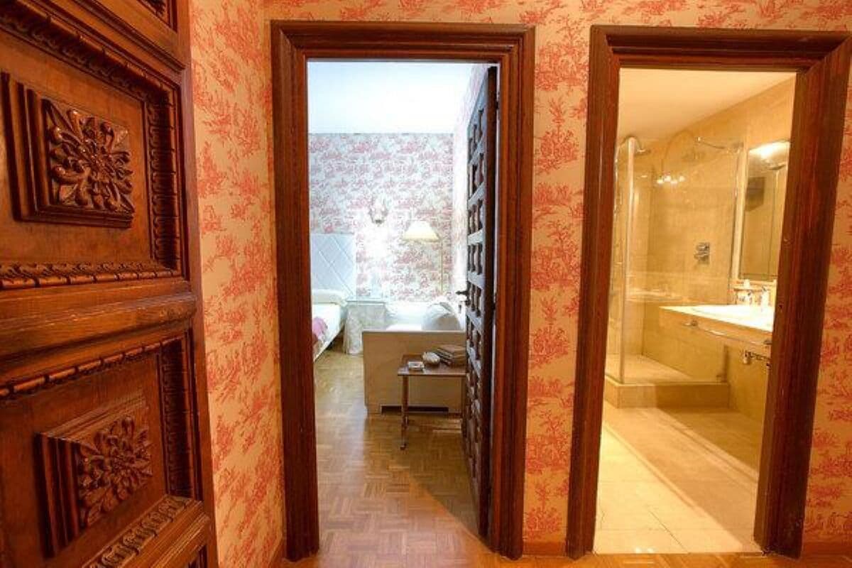 Un couloir menant à une salle de bain équipée d’une douche et d’un lavabo.