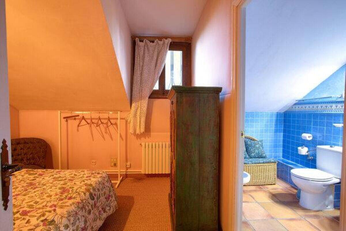A bedroom with a bed, a radiator, and a window with curtains.