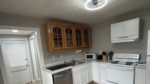 Une cuisine moderne avec des meubles blancs, un lave-vaisselle en acier inoxydable, une cuisinière et un four à micro-ondes.