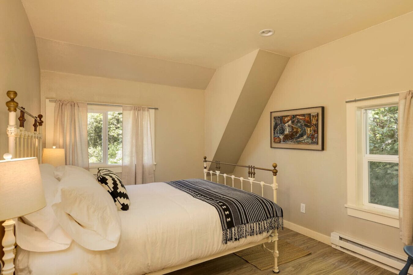 Un dormitorio con una cama, una ventana, un cuadro y un radiador.