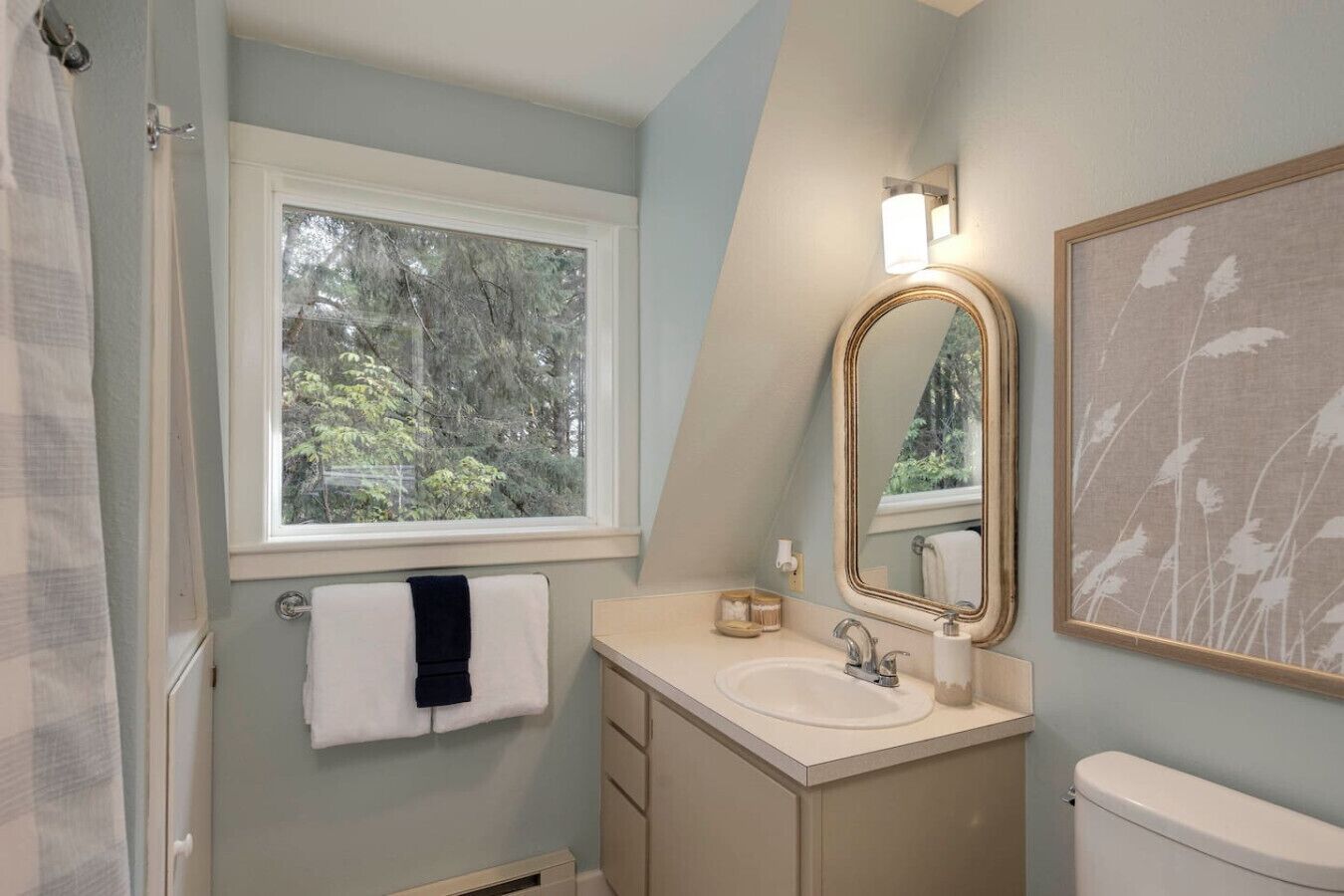 Une salle de bain avec une fenêtre, un lavabo, un miroir et des toilettes.