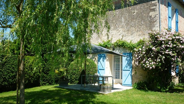 Ein rustikales Haus mit Terrasse, Tisch und Stühlen sowie einem Garten.