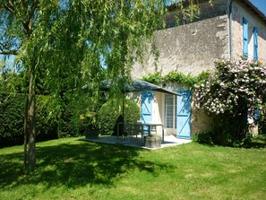 A rustic house with a patio, a table and chairs, and a garden. - Gîte Le Logis de Faugerit In the Marais Poitevin, quiet, flowery, green site (Frontenay-Rohan-Rohan)