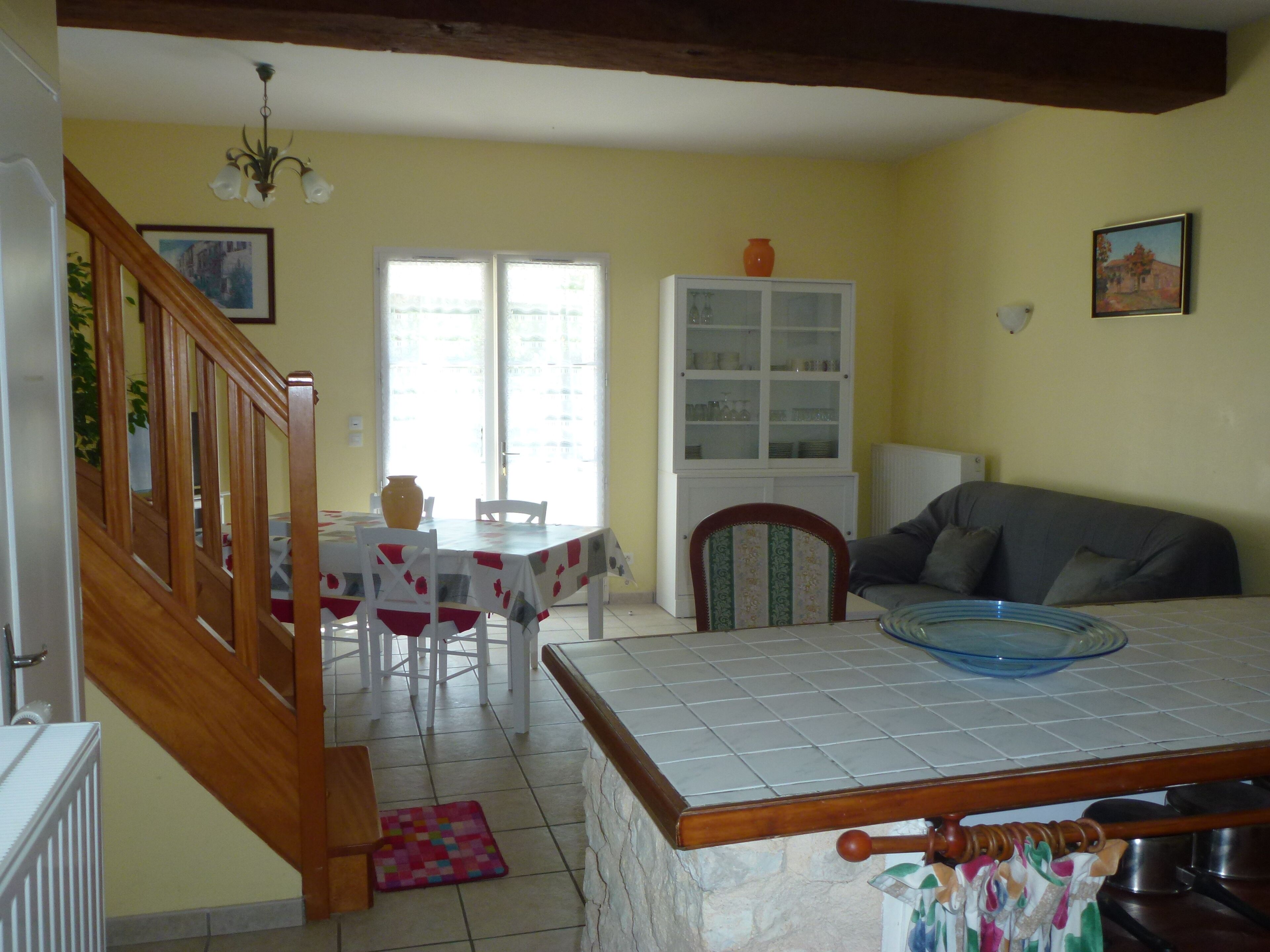 Une cuisine avec une table à manger, des chaises, un buffet et un escalier.