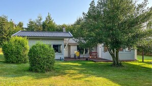 A single-story house with a tiled roof, a patio with a table and chairs, and a small shed in the backyard. - 3 bedroom gorgeous home in Sæby (Sæby)
