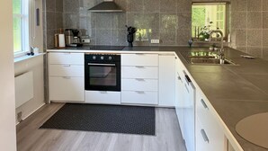 A modern kitchen with a built-in oven, white cabinetry, granite countertops, and a black mat at the entrance. - 3 bedroom gorgeous home in Sæby (Sæby)