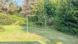A metal swing set in a grassy area surrounded by dense foliage. - 3 bedroom gorgeous home in Sæby (Sæby)