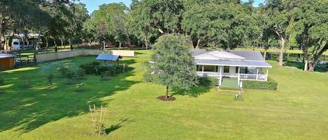 A residential property with a well-maintained lawn, a small garden, and a house with a porch.