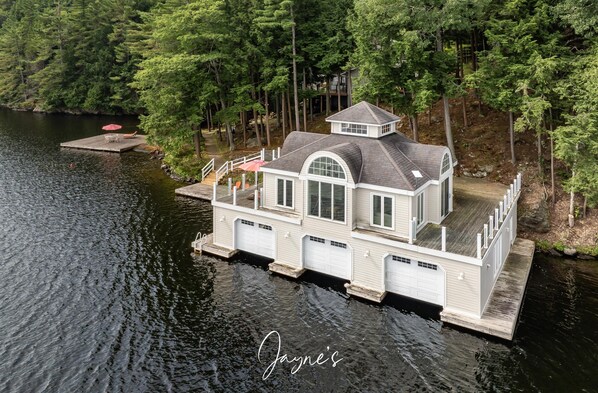 A houseboat with a dock, large windows, and a covered deck area.