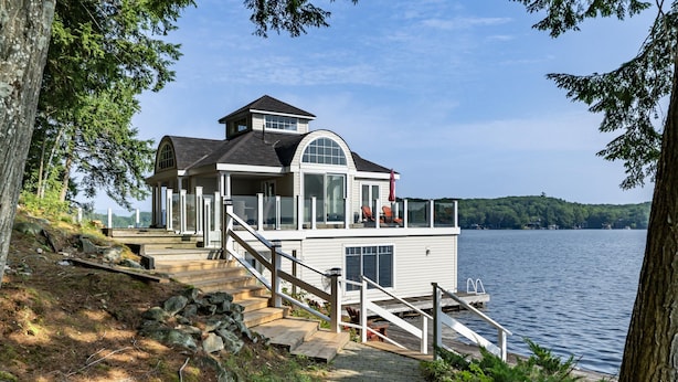 Una casa frente al lago con una terraza, una escalera y vistas al lago.
