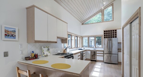 A modern kitchen with a central island, wooden cabinets, and a stainless steel refrigerator.