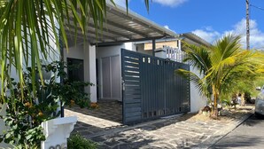 Una casa moderna con una verja metálica gris, el número 205, y un camino de entrada pavimentado.