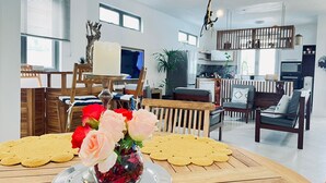 Una sala de estar moderna con una mesa de comedor lista para una comida, que incluye un jarrón con flores y un plato de galletas.