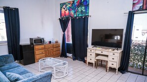 Ein Wohnzimmer mit einer Couch, einem Couchtisch, einem Fernseher, einer Mikrowelle und einer Kommode.